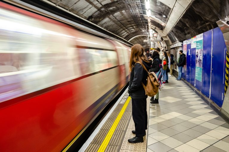 A passenger stands in the platform of a London Underground Station as a train arrives.