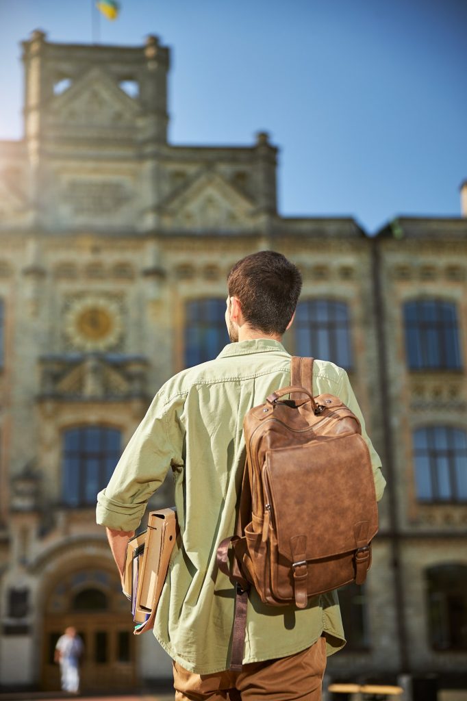 Young dark-haired man with textbooks going ahead