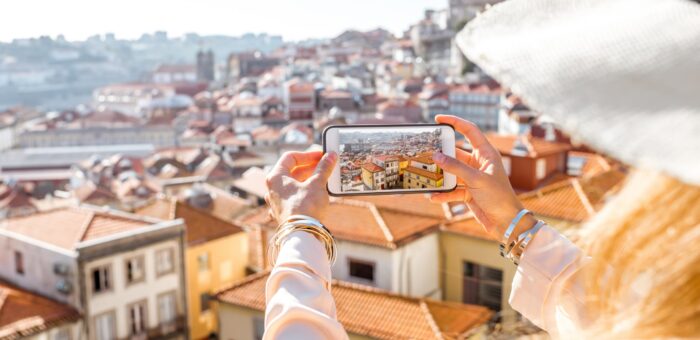 Woman photographing with phone cityscape view on the old town of Porto city in Portugal